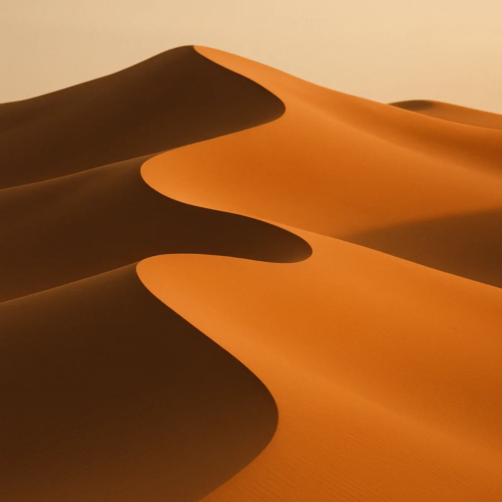 Close-up of undulating golden sand dunes with contrasting light and shadow under a clear sky.