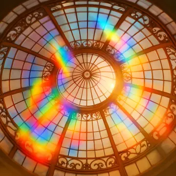 An ornate glass dome ceiling with a bright rainbow reflection arcing across its surface.